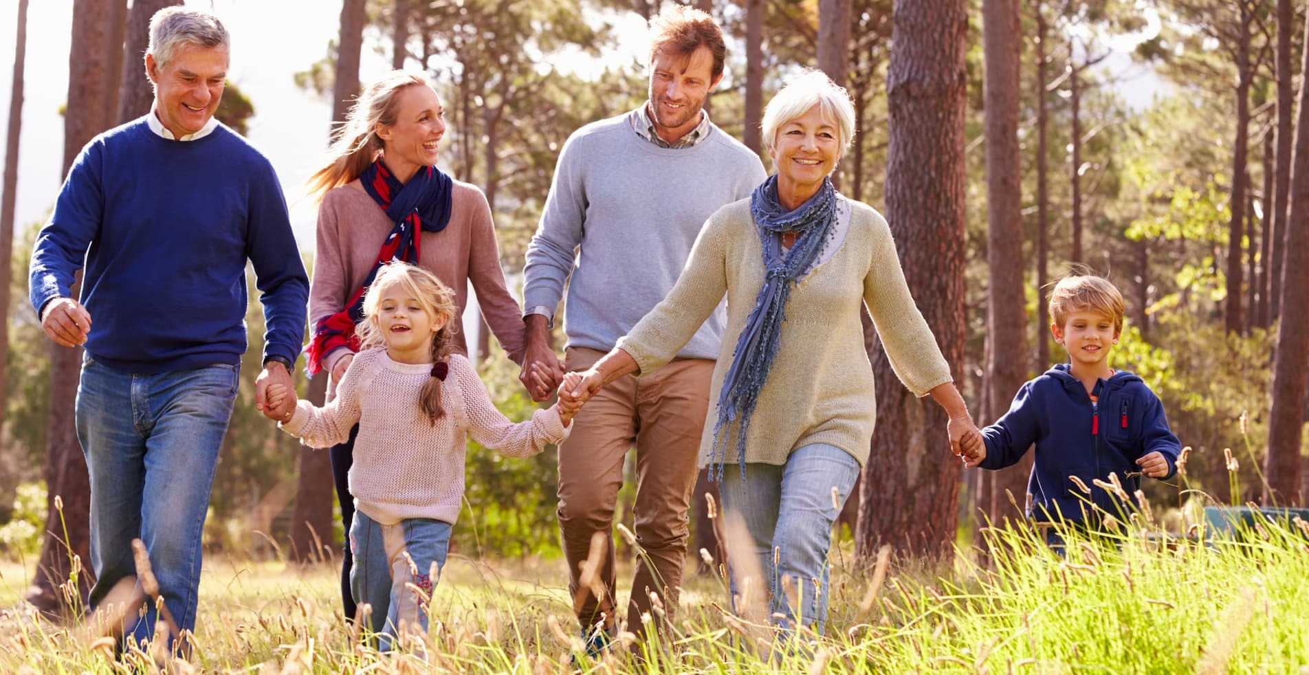 A happy family of 6 taking a walk in some woods.